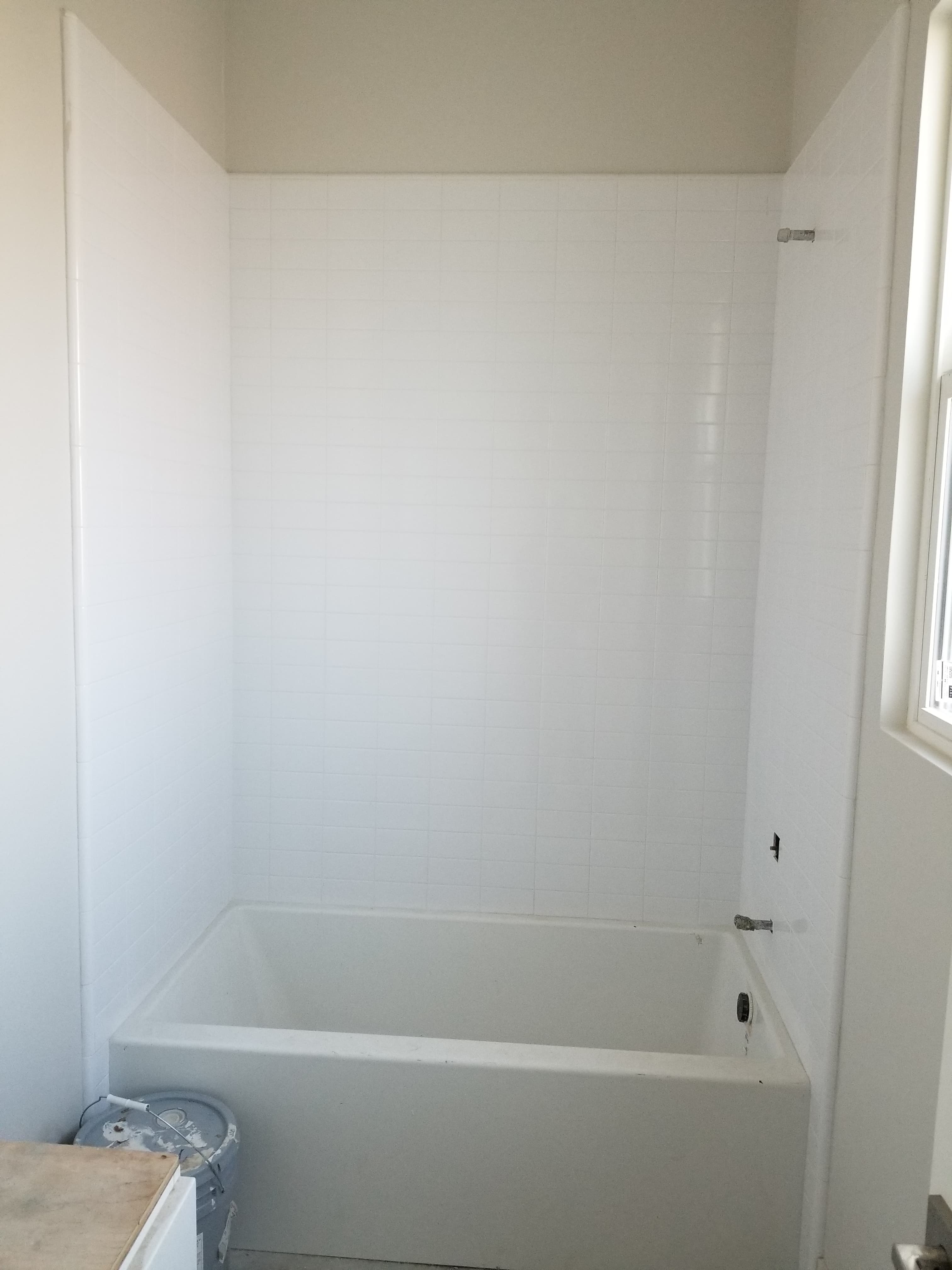Finished La Quinta shower install with white subway tile walls and accent window