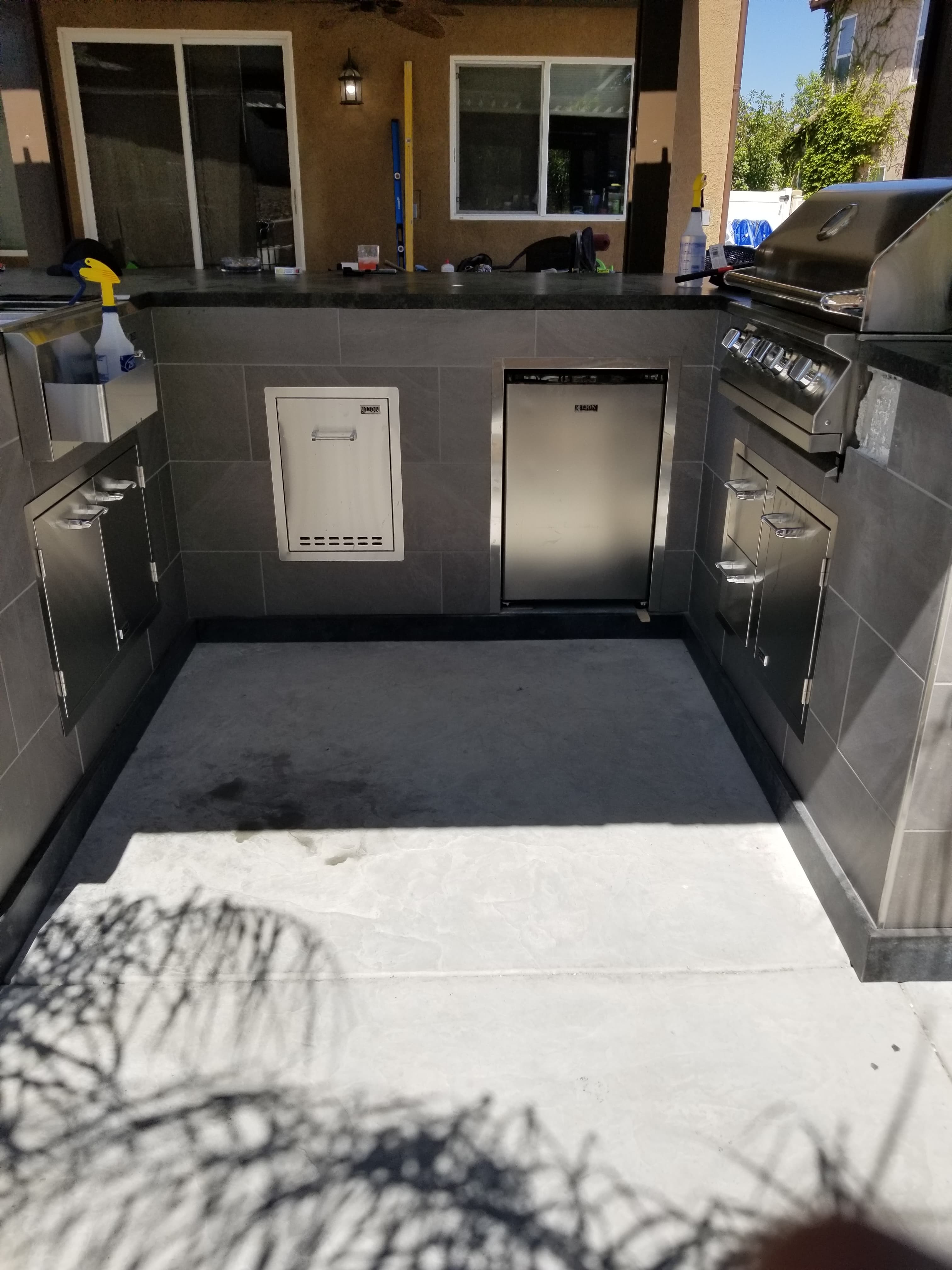 Finished Menifee outdoor BBQ kitchen wrapped in dark gray porcelain with stainless grill, sink, and built-in storage cabinets