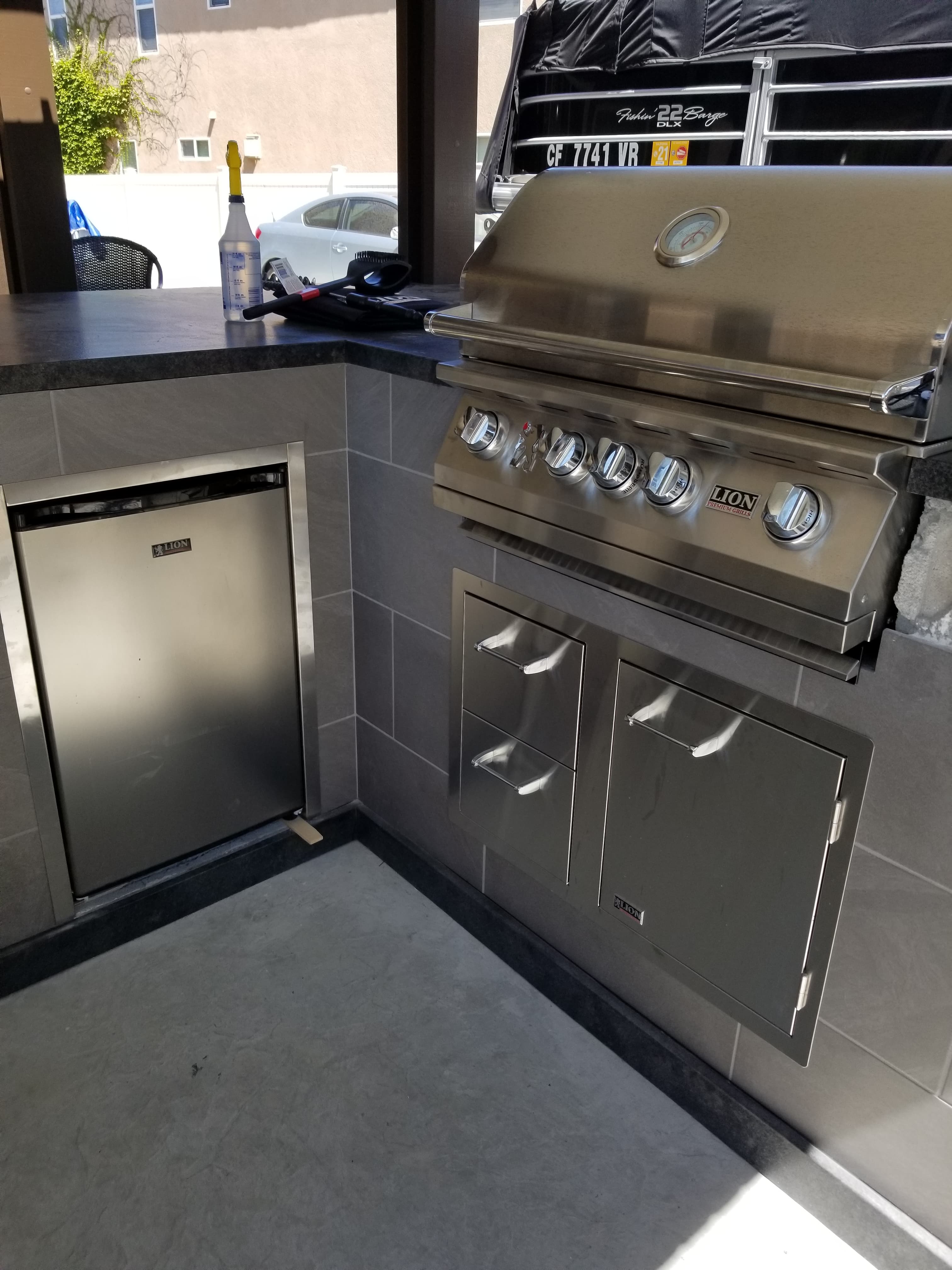 Lion-brand stainless BBQ grill set into a Menifee outdoor kitchen surround clad in large-format dark gray porcelain