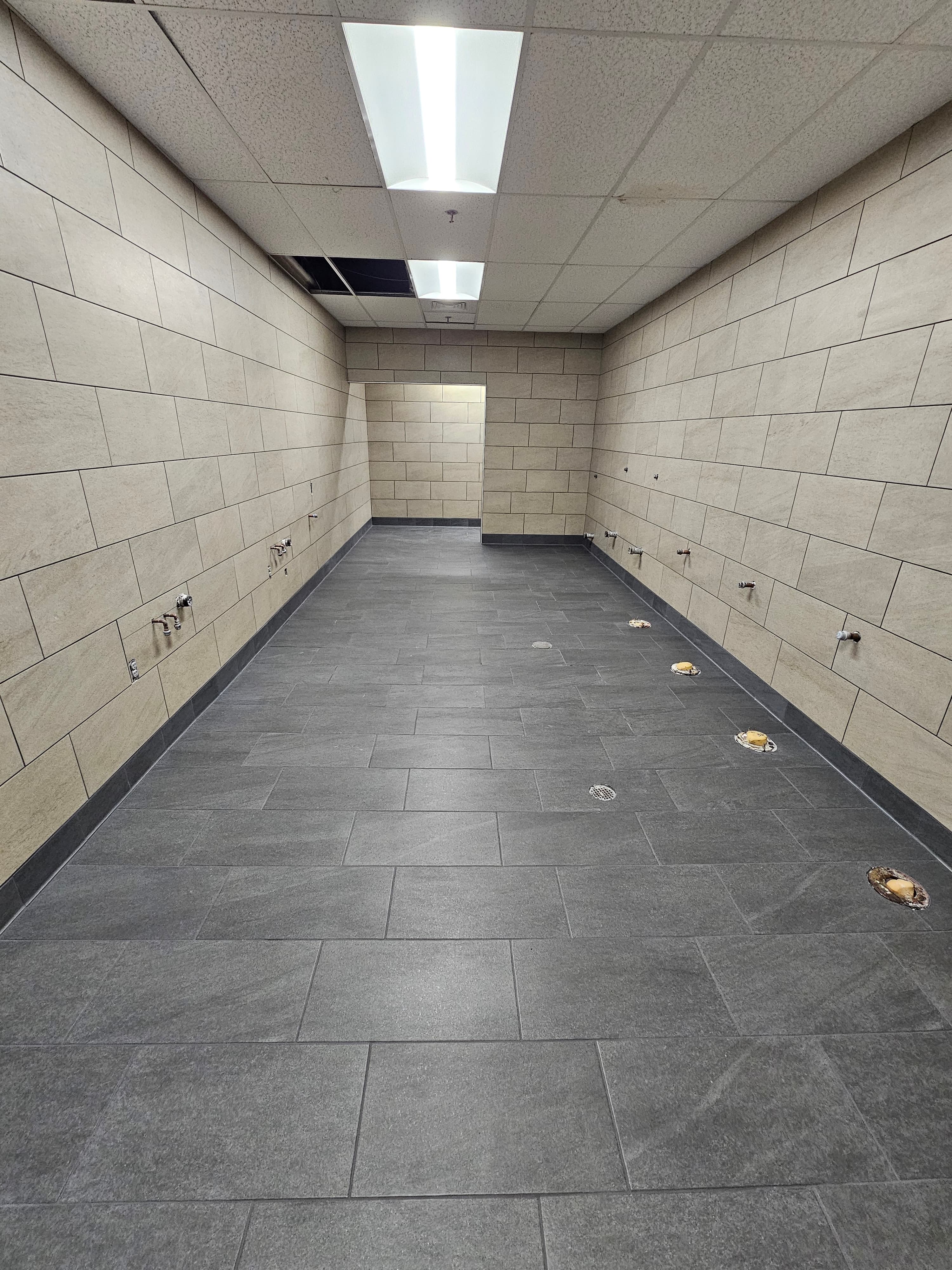 Lowe's commercial restroom in Menifee with oversized gray porcelain wall tile and dark slate-look floor