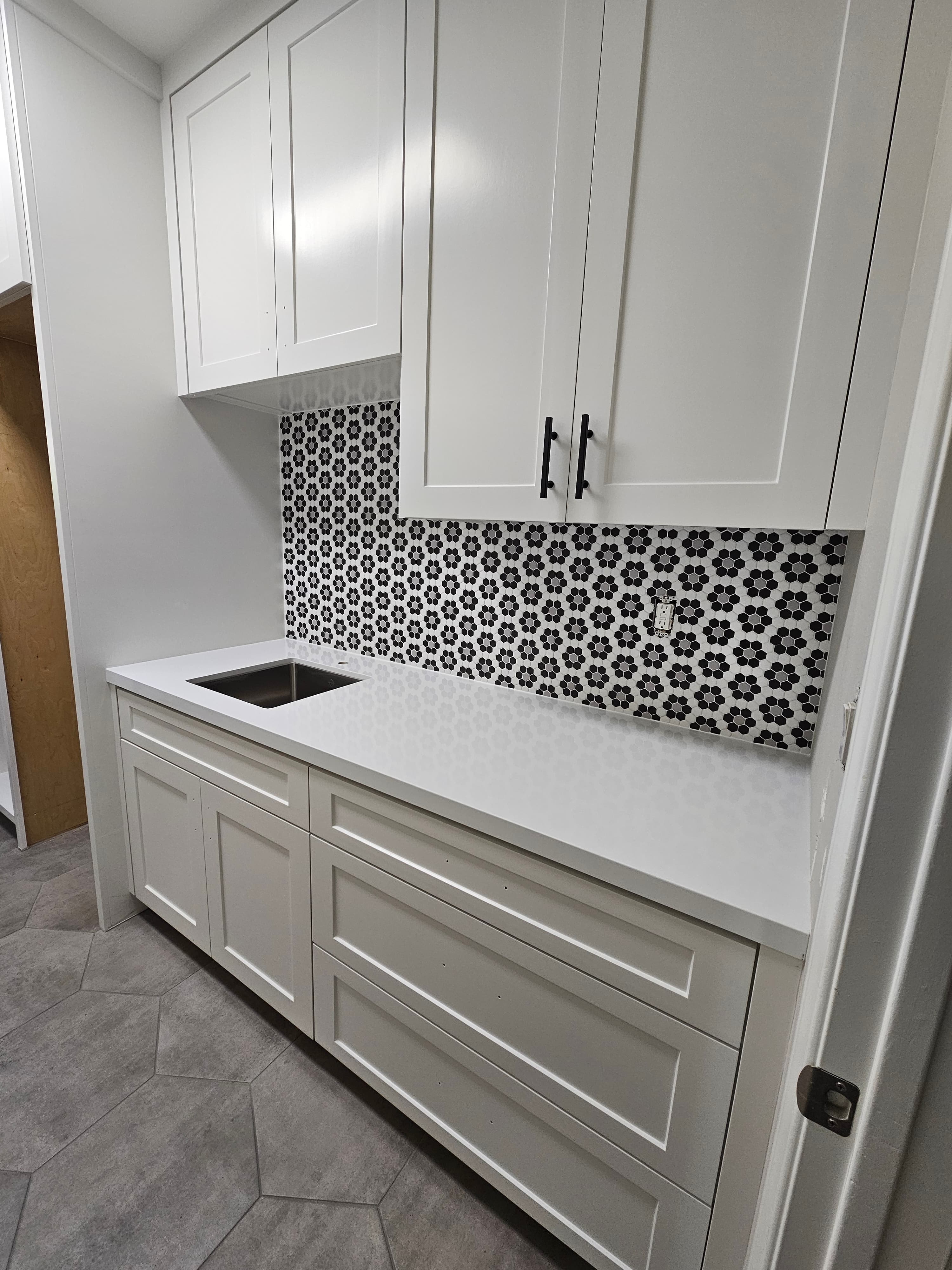 Rancho Santa Margarita butler's pantry with black-and-white floral hexagon mosaic backsplash above quartz counter and white shaker cabinetry