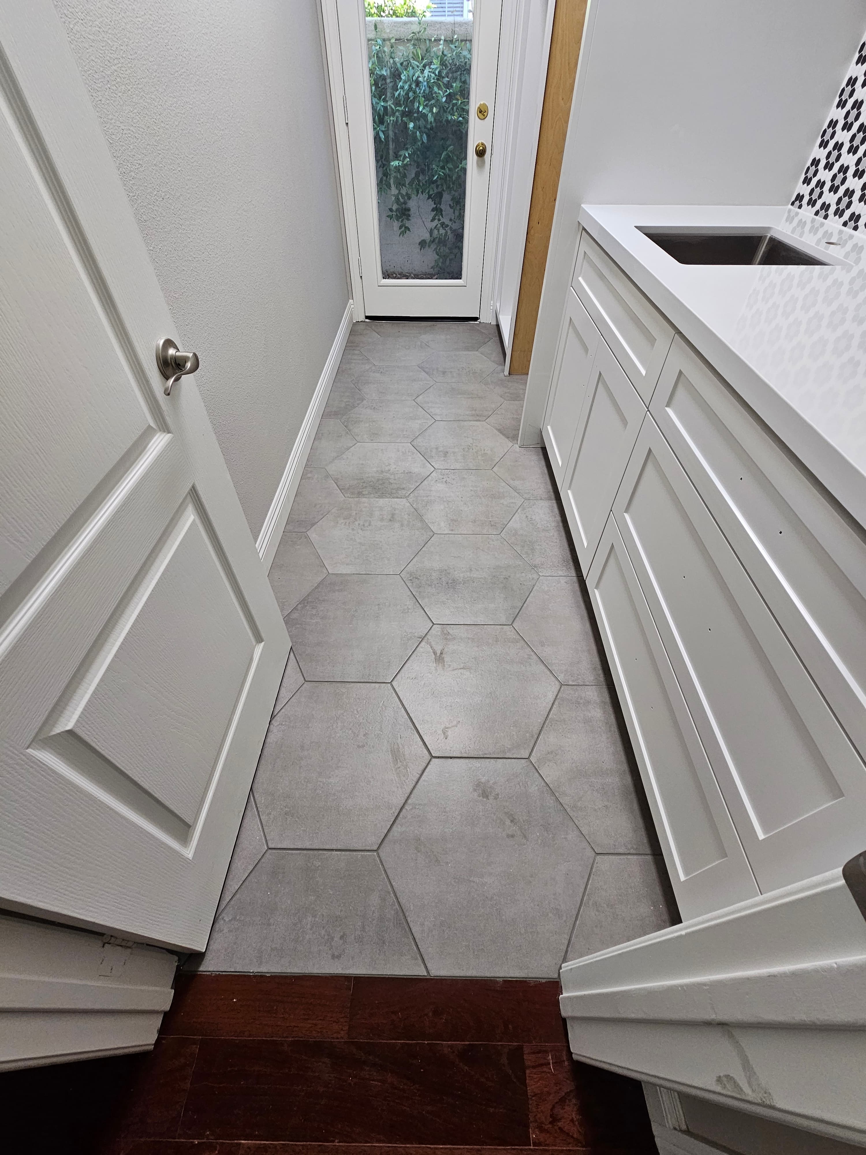 Large-format hexagon stone tile flooring in a Santa Margarita butler's pantry with white cabinetry and glass exterior door